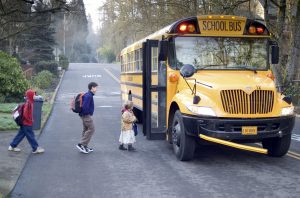 Three young children climbing aboard schoolbus