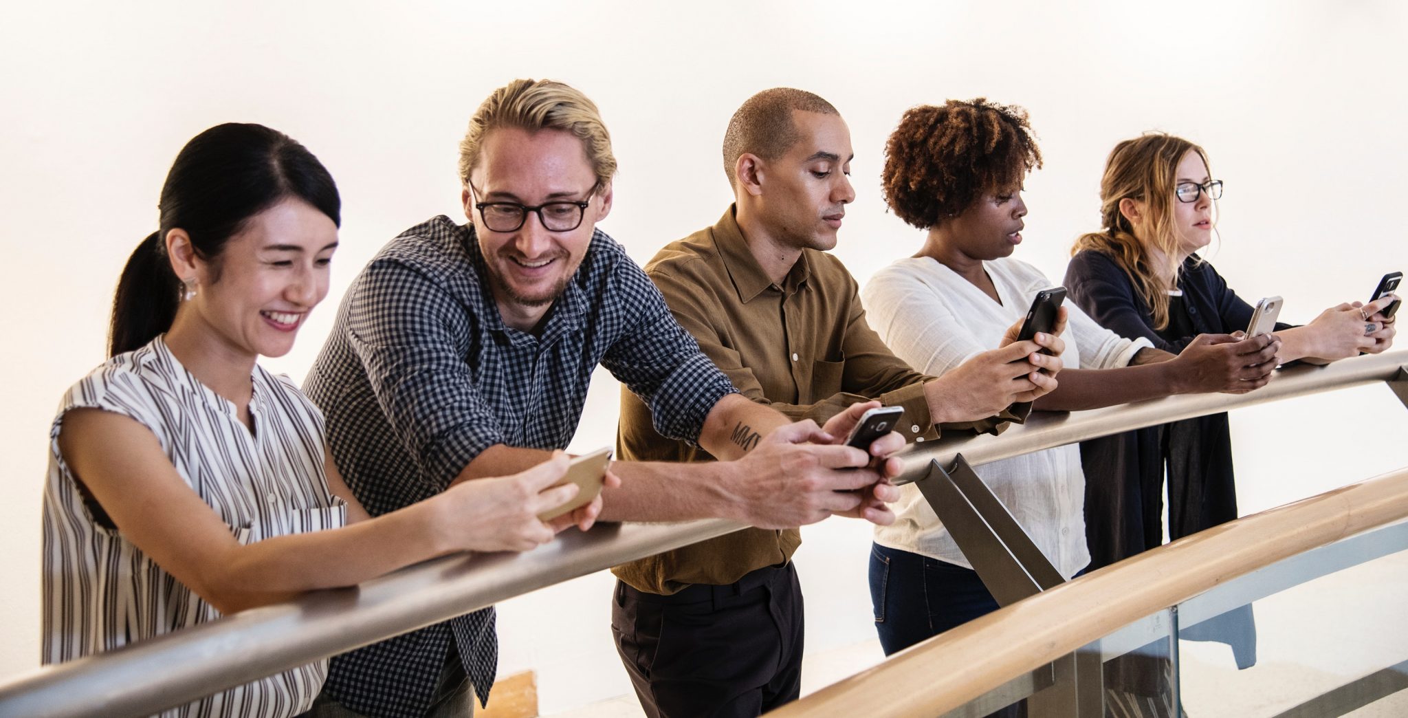 Adults standing around a table all looking at their phones and talking