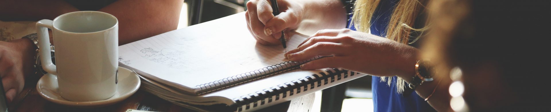 adults taking notes on notebooks and laptops