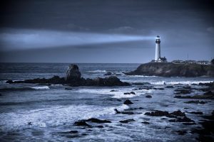 Lighthouse on a rocky beach at night.