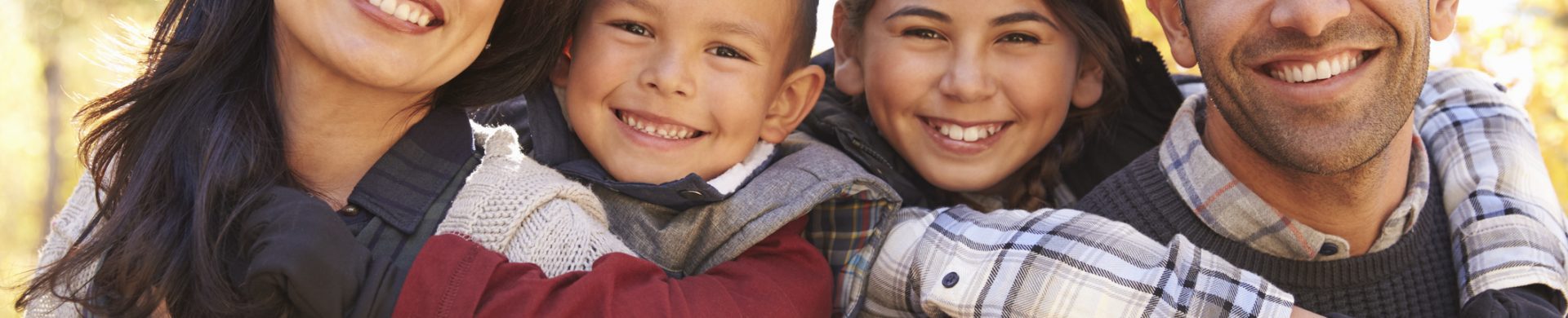 Portrait of happy parents piggybacking kids outdoors