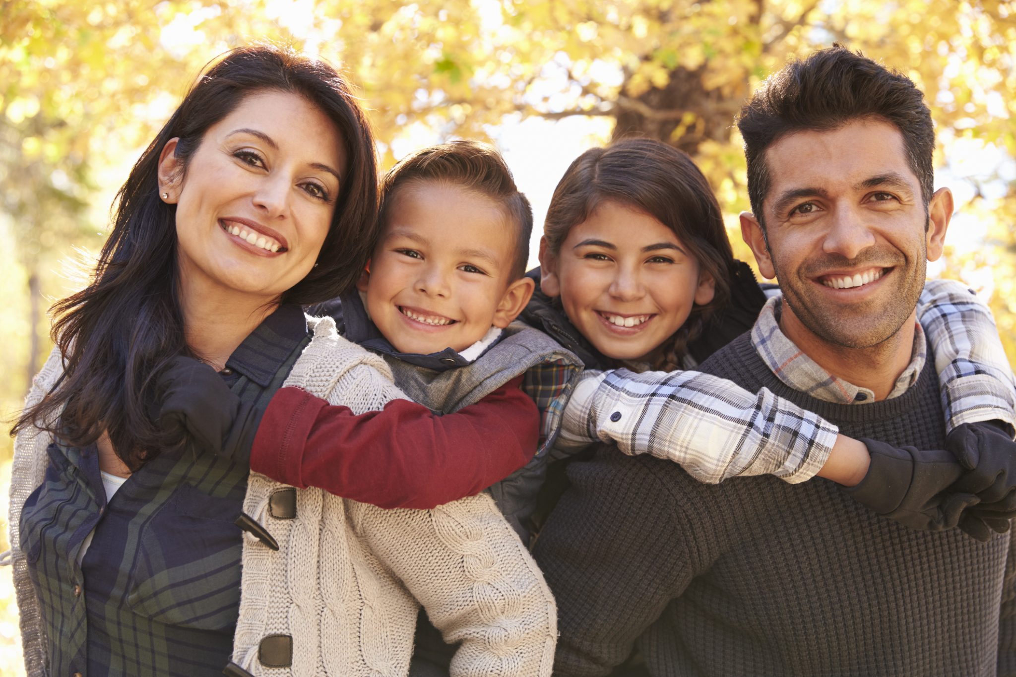 Portrait of happy parents piggybacking kids outdoors