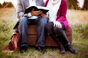 Man and woman reading bible together outdoors
