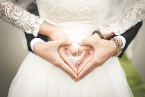Bride and groom making shape of heart with their hands