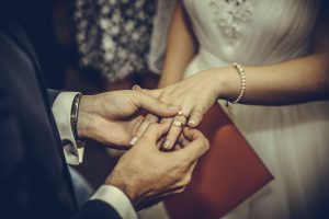 Groom sliding wedding ring onto bride's finger