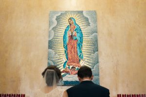 Couple kneeling in front of Mary painting
